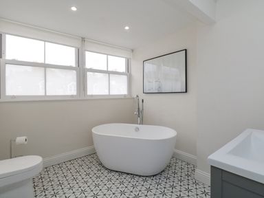 A bathroom with a freestanding bathtub toilet sink and patterned floor at Forty Five in Keswick
