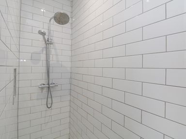A shower area with wall-mounted dual showerheads and white subway tile walls at Forty Five in Keswick