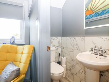 A bathroom with a toilet and sink next to a room with a yellow chair at Tyn Rallt Ice Cream Farm in Malltraeth near Newborough