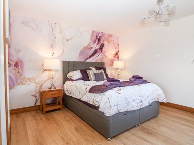 A bedroom with a bed bedside tables lamps and a decorative wall at Tyn Rallt Ice Cream Farm Malltraeth near Newborough