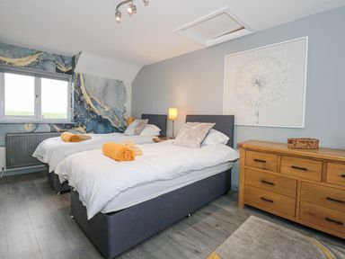 A bedroom with two single beds a wooden dresser and a window at Tyn Rallt Ice Cream Farm Malltraeth near Newborough