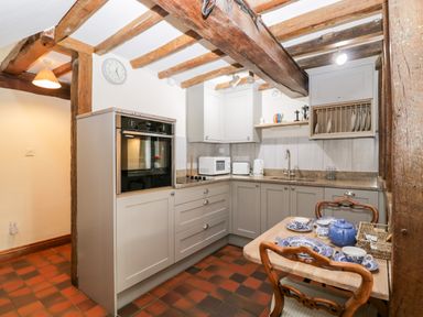 A kitchen with wooden beams on ceiling and tiled floor at Well Cottage in Moreton-In-Marsh
