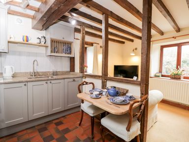 A kitchen with gray cabinets and a small dining table set with blue and white china at Well Cottage in Moreton-In-Marsh