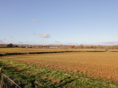 A farmland with green and brown fields under a clear sky at Well Cottage in Moreton-In-Marsh