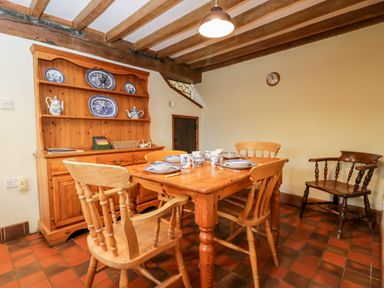 A dining room with a wooden table set for four and a dresser with blue and white china at Stable Cottage in Moreton-In-Marsh