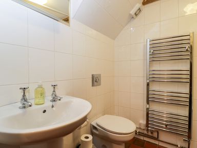 A bathroom with a sink a bottle of hand wash a toilet and a towel radiator at Stable Cottage in Moreton-In-Marsh