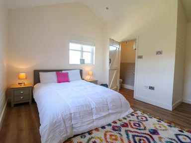 A bedroom with a bed lamps on bedside tables and a patterned rug at The Stables in Tafarn-Y-Gelyn