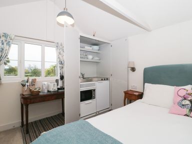 A bedroom with a built-in kitchenette cupboard and a small wooden table with kitchen appliances at The Potting Shed in Combe near Langport