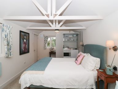 A bedroom with a double bed and a kitchenette at The Potting Shed in Combe near Langport