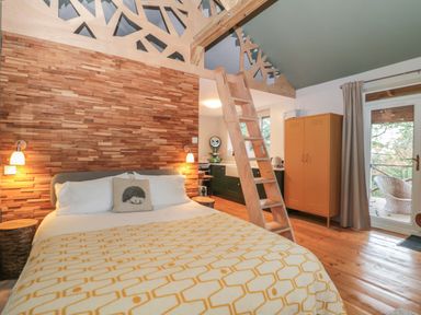 A bedroom with a bed a wooden ladder a kitchen area and a wardrobe at Pear Tree Lodge in Combe near Langport