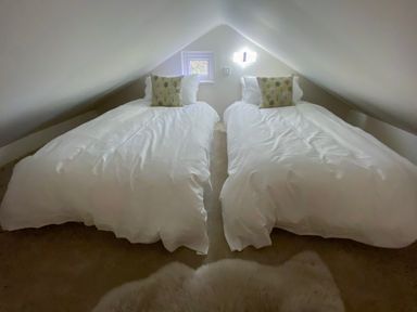 A bedroom with two single beds with white bedding and pillows under a sloped ceiling at Pear Tree Lodge in Combe near Langport