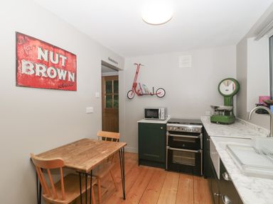 A kitchen with a wooden table and chairs a microwave stove and a green scale at Pear Tree Lodge in Combe near Langport