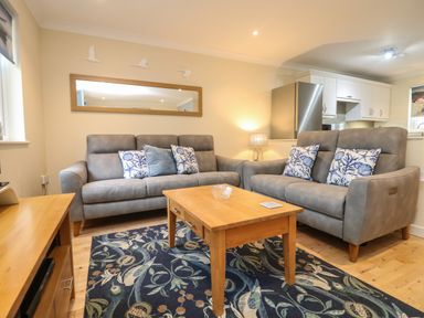 A living room with two grey sofas a wooden coffee table and a patterned rug at Manuka in Falmouth