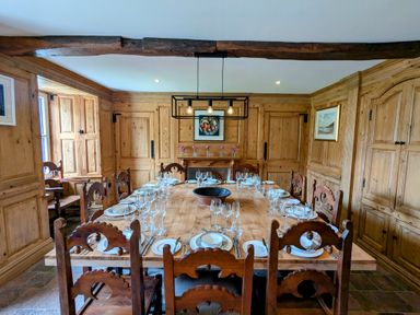 A dining room with a large wooden table set with plates and glasses surrounded by wooden chairs and wooden paneled walls at Glanduad Fawr in Newport Pembrokeshire