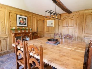 A dining room with a wooden table and chairs wooden paneled walls and framed artwork at Glanduad Fawr in Newport Pembrokeshire