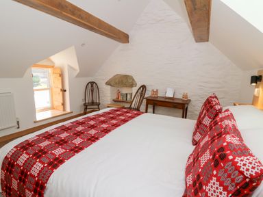 A bedroom with a bed a wooden table two chairs and a small window at Glanduad Fawr in Newport Pembrokeshire
