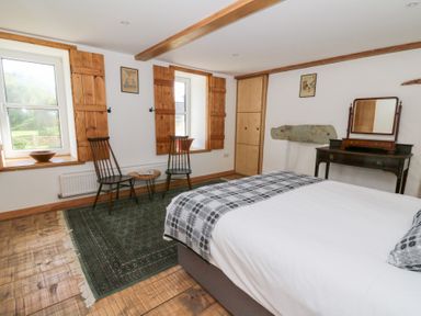 A bedroom with a bed two chairs a small table a wardrobe and a dressing table at Glanduad Fawr in Newport Pembrokeshire
