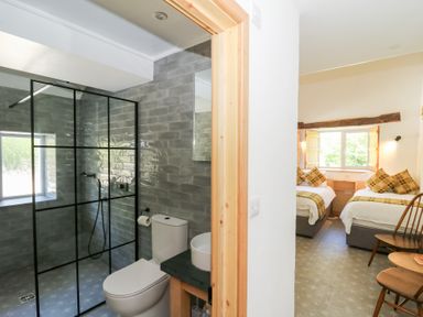 A bathroom with a toilet and glass shower and a bedroom with two single beds at Glanduad Fawr in Newport Pembrokeshire
