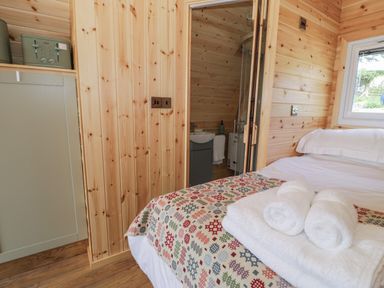 A small bedroom with a bed covered with towels next to a doorway leading to a bathroom at Tarrenhendre Pod in Llanegryn near Tywyn