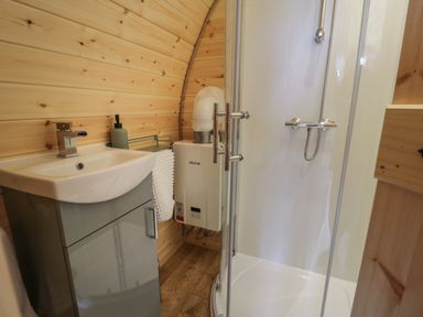 A bathroom with a sink cabinet soap dispenser towel heater and a shower cabin at Tarrenhendre Pod in Llanegryn near Tywyn