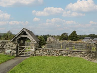 An outdoor stone-walled cemetery with a wooden gate and a path leading inside at Tarrenhendre Pod in Llanegryn near Tywyn