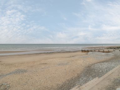 A sandy beach with some pebbles and wooden groynes by the sea at Tarrenhendre Pod in Llanegryn near Tywyn