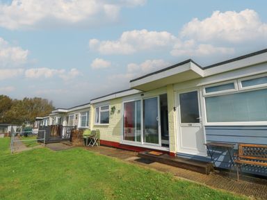A row of single-story residential units with outdoor furniture on a grassy area at Culver View in Sandown