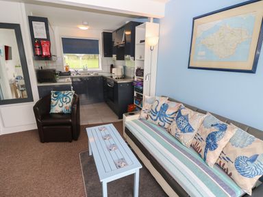 A living room with a sofa and cushions next to a blue wall with a map and an armchair facing a blue coffee table at Culver View in Sandown