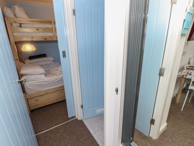 A hallway with blue doors leading to a small bedroom with wooden bunk beds at Culver View in Sandown