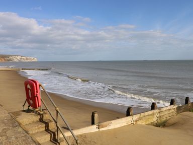 A sandy beach with small waves and wooden groynes at Culver View in Sandown