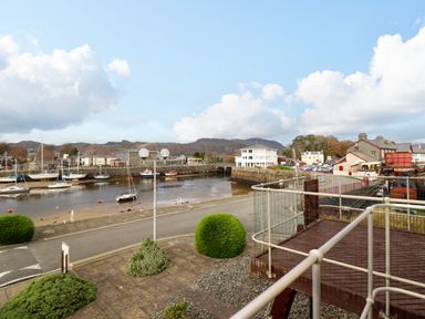 A harbor with boats moored near a stone quay and buildings in the background at Branwen in Porthmadog