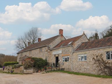 Stone building with multiple chimneys and potted plants near entrance at Primrose in Higher Wambrook near Chard