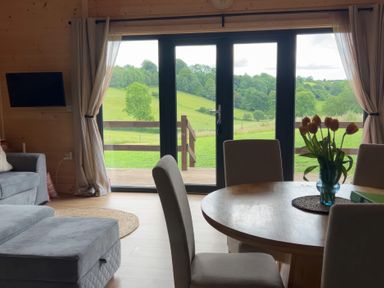 A living room with a sofa and table looking out to the fields at Primrose Higher Wambrook near Chard