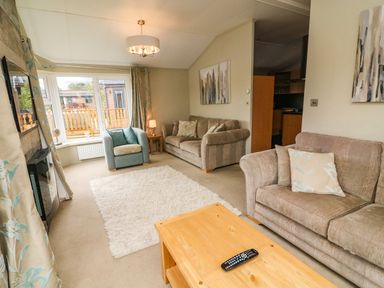A living room with sofas armchair wooden coffee table and window at Lakeside 12 in Carnforth