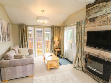 A living room with a sofa coffee table tv and fireplace at Lakeside 12 in Carnforth