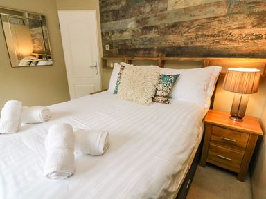 A bedroom with a bed with white linens and rolled towels on the bed at Lakeside 12 in Carnforth