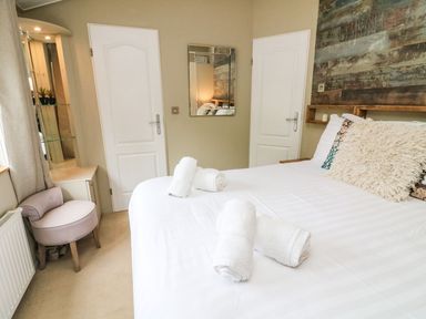 A bedroom with a bed that has white linens and towels rolled on top at Lakeside 12 in Carnforth