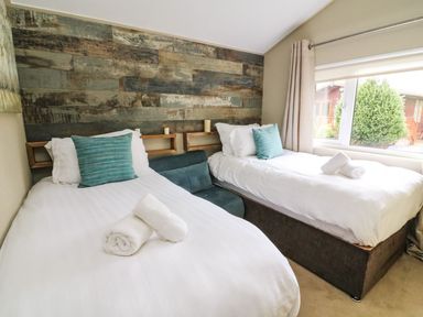 A bedroom with two single beds and a window showing greenery at Lakeside 12 in Carnforth