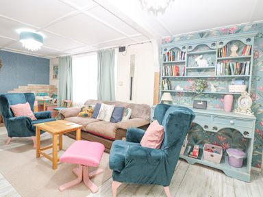 A living room with armchairs a sofa wooden tables and a bookshelf at White Rabbit Cross Lane Eccles-On-Sea