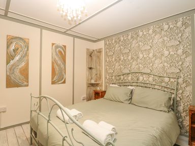 A bedroom with a metal frame bed and rolled towels on the bed at White Rabbit Cross Lane in Eccles-On-Sea