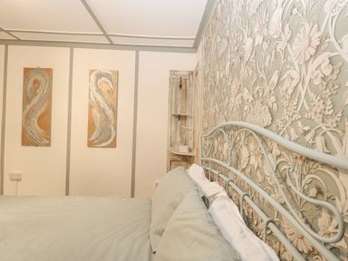 A bedroom with a bed and patterned wallpaper at White Rabbit Cross Lane in Eccles-On-Sea