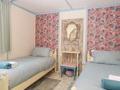 A bedroom with two single beds and a small table with mirror at White Rabbit Cross Lane in Eccles-On-Sea