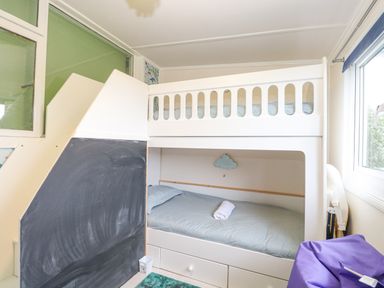 A children's bedroom with a white bunk bed a chalkboard side panel and a purple bean bag chair at White Rabbit Cross Lane in Eccles-On-Sea