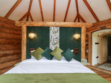 A bedroom with a bed with green pillows and a green and white bedspread inside a log cabin at Copper Lodge in Chulmleigh
