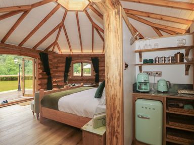 A bedroom with wooden bed and kitchenette with mint appliances at Copper Lodge in Chulmleigh