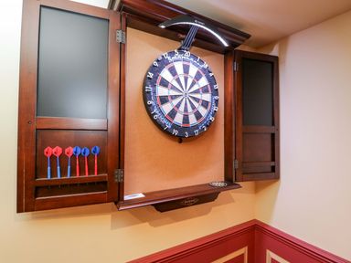 A dartboard and darts mounted on a cabinet in a game room at White House