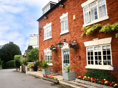 A brick building with white framed windows and flowerpots outside on a street at Yes Deer in Ashbourne