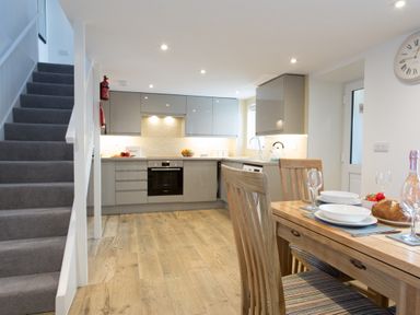 A kitchen and dining area with wooden table and chairs and stairs leading up at Cornish Views in Camborne
