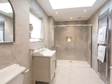 A bathroom with a shower with glass doors a vanity sink a toilet and a towel rack at Cornish Views in Camborne