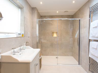 A bathroom with a double sink vanity and a glass-enclosed walk-in shower with towels on a chrome heated rack at Cornish Views in Camborne